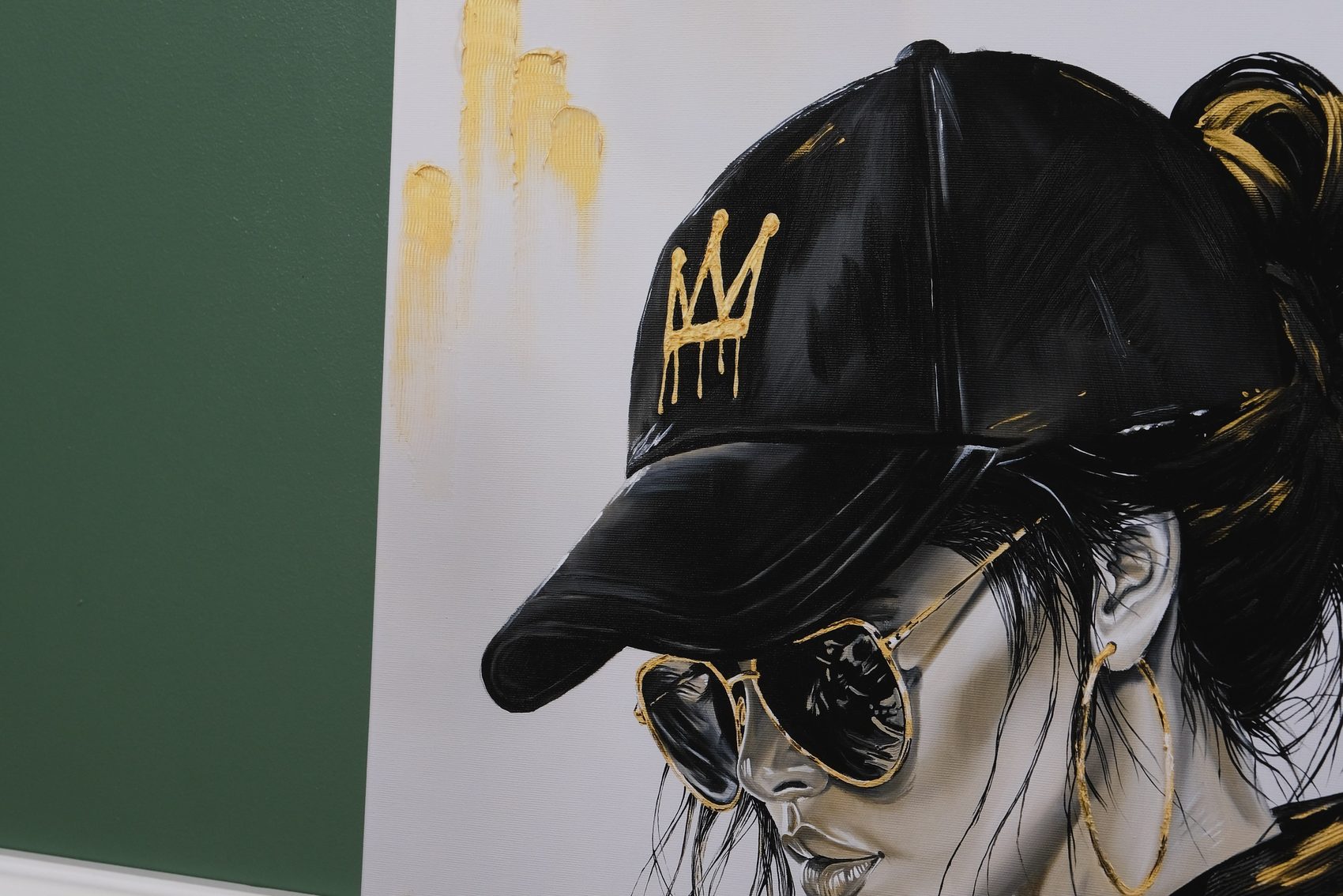 Detailaufnahme des Porträts: Kappe mit goldener Tropfen-Krone, Sonnenbrille mit Goldrahmen und Creolen