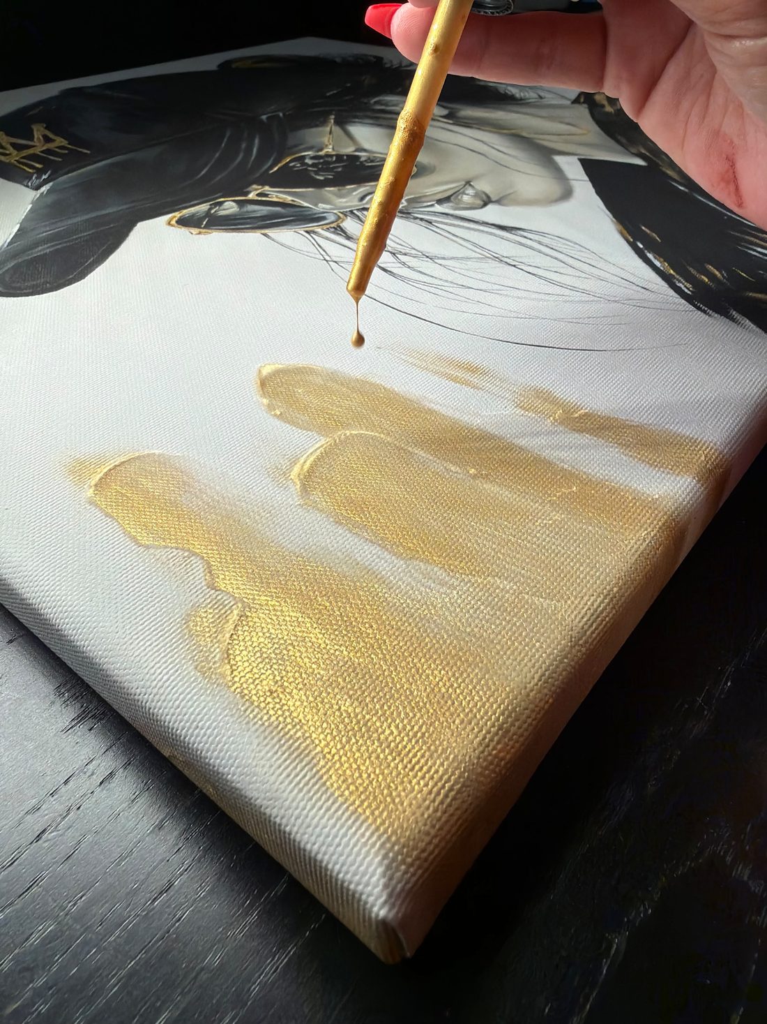 Goldfarbe tropft von einem Pinselstiel auf die Leinwand