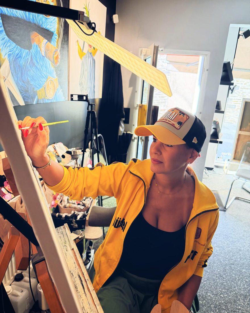 Martina Ixfeld in gelber Jacke und Cap beim Malen im Atelier in Andernach